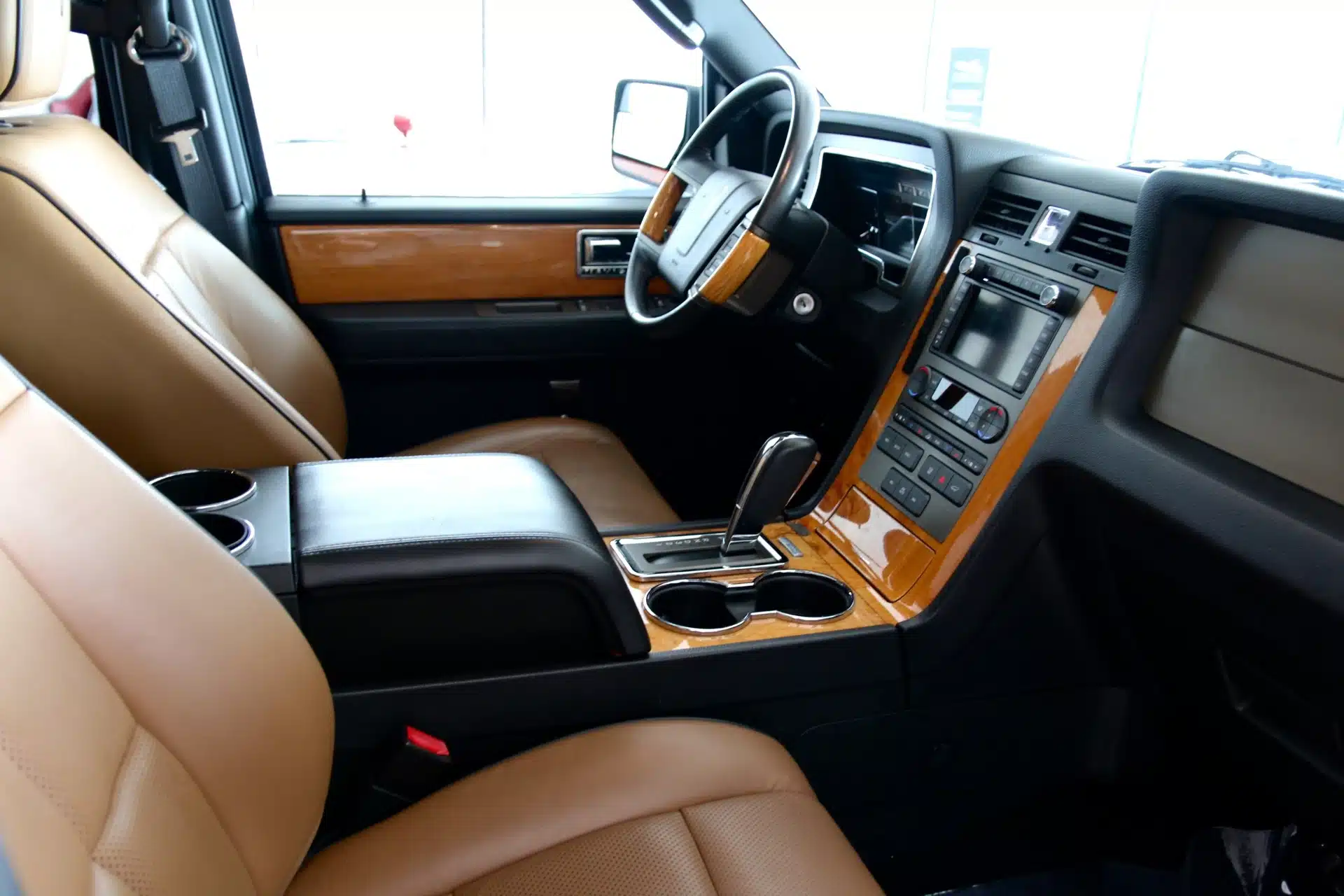 Interior of a used 2013 Lincoln Navigator L showing beige leather seats, woodgrain trim, and a touchscreen infotainment system.
